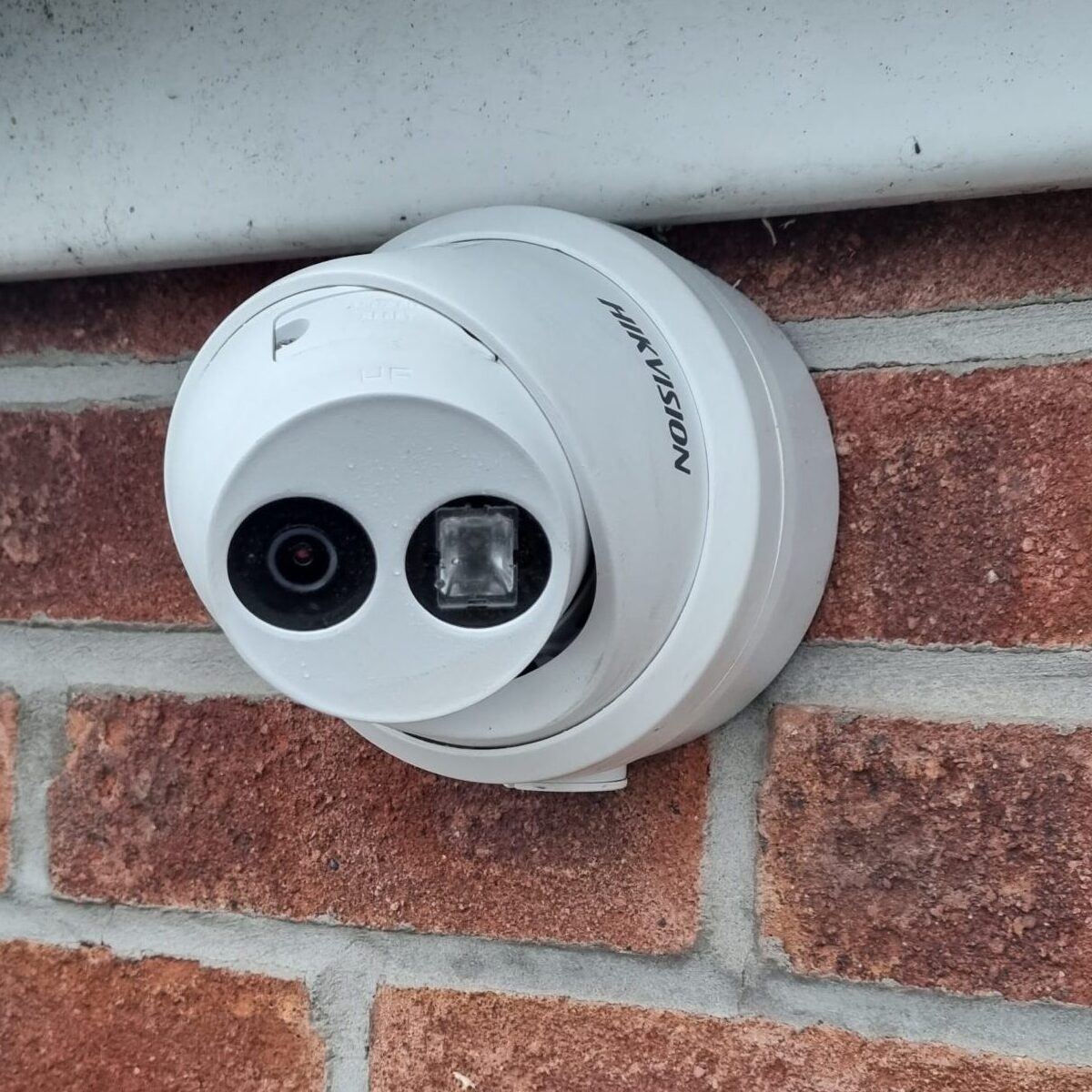 A whit CCTV camera fixed to a brick wall