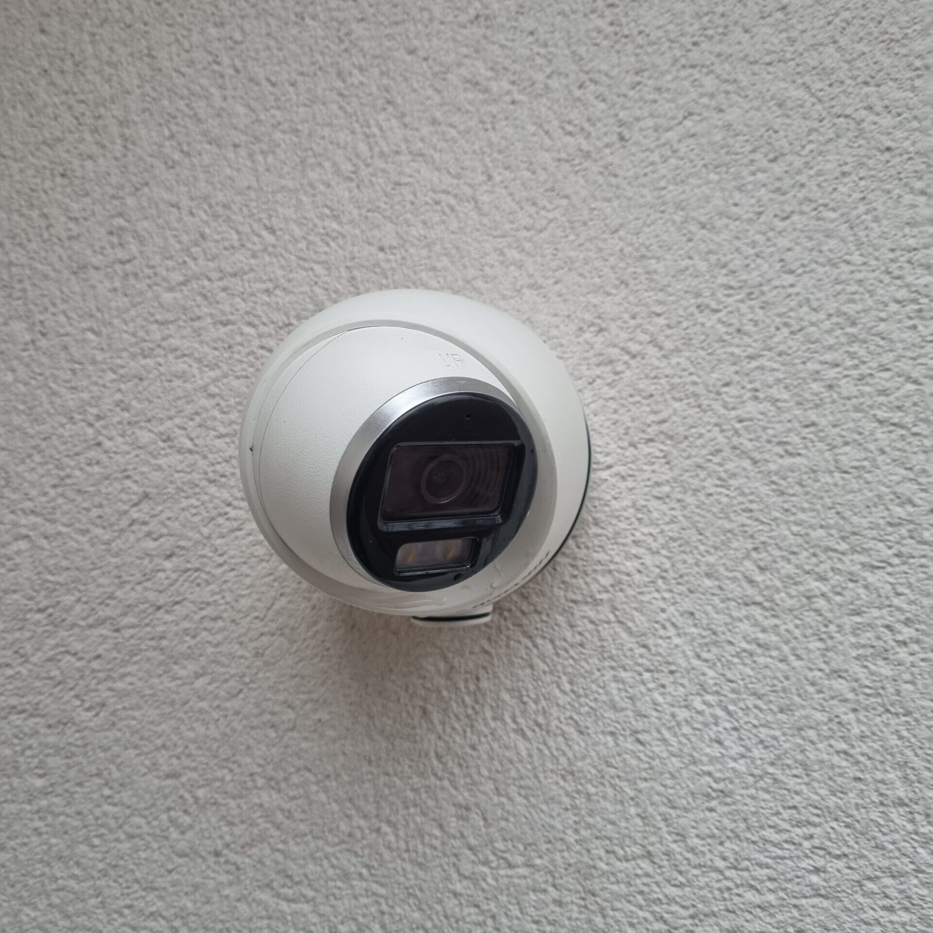 A whit CCTV camera fixed to a white wall