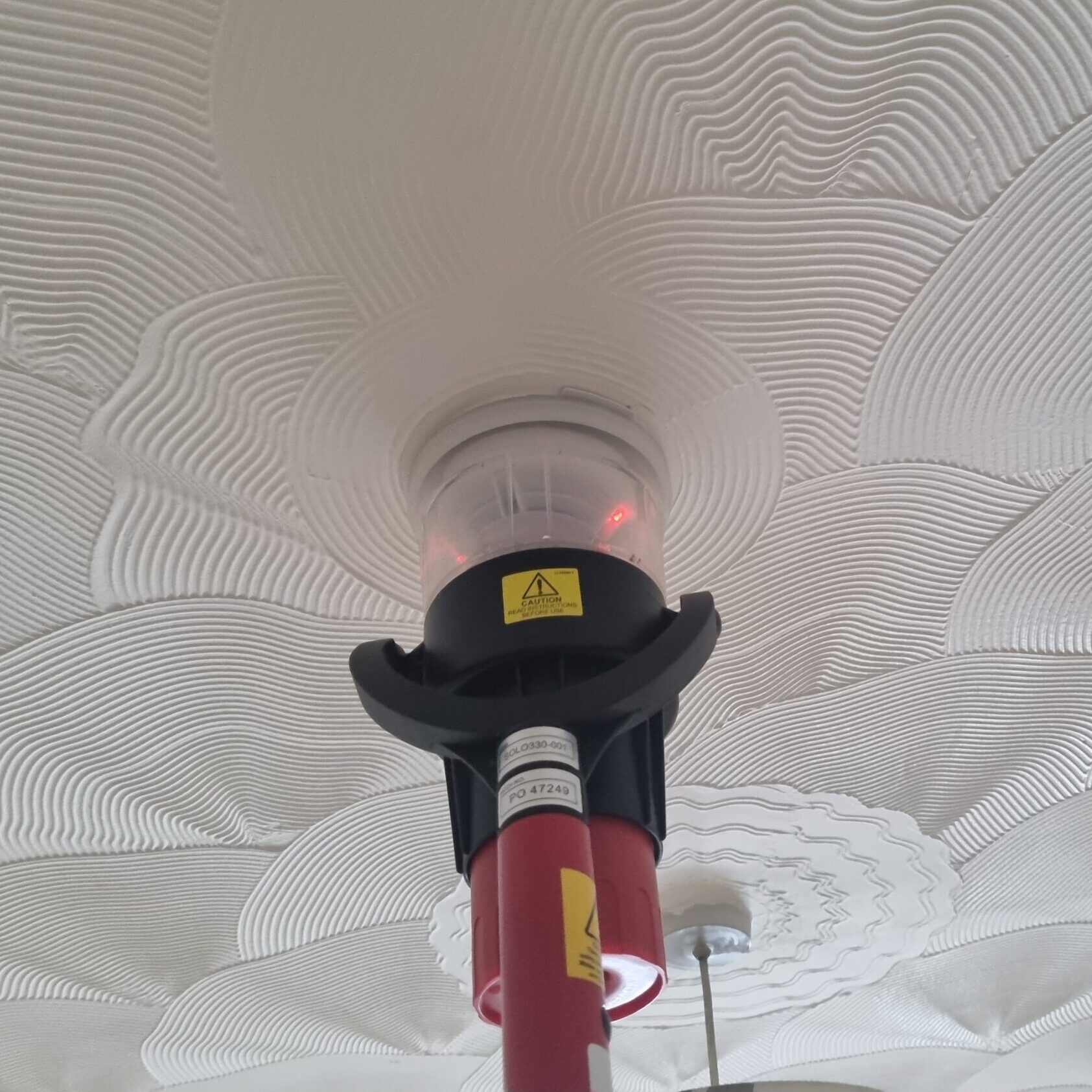 Image of smoke detector on a fire alarm system being tested with a smoke test kit.