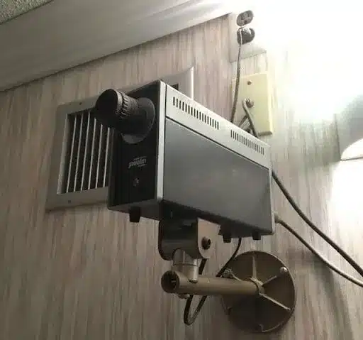 Image of an old CCTV camera mounted on a wall with cables coming out the back