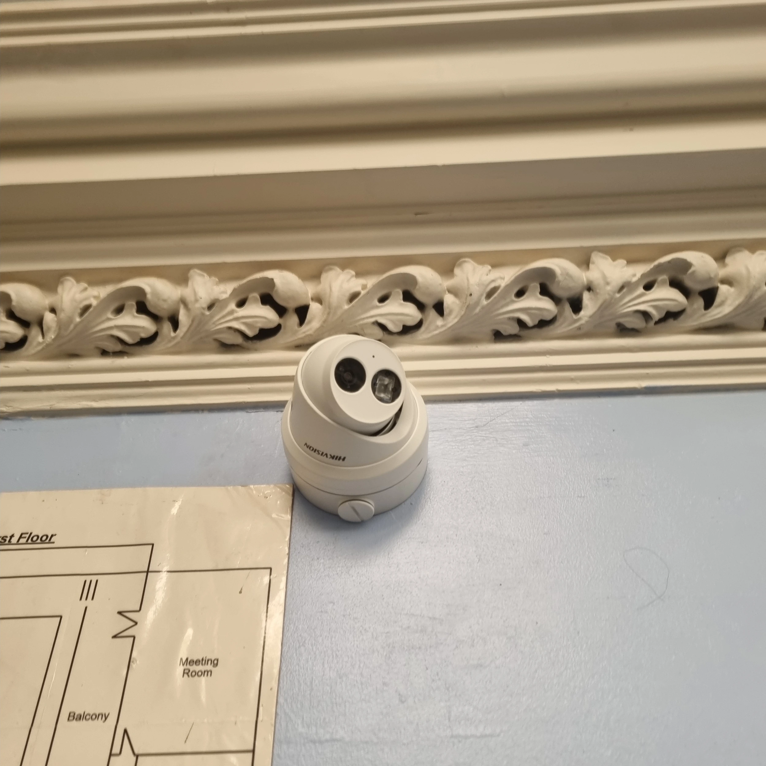CCTV camera mounted on a blue wall within a building.